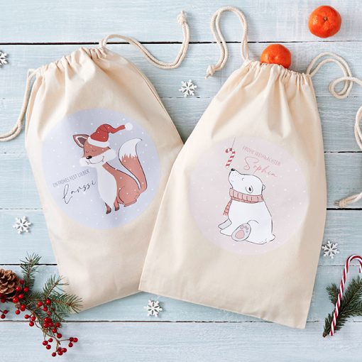 Zwei Geschenkbeutel mit Weihnachtsmotiven: ein Fuchs und ein Hund in festlicher Kleidung.